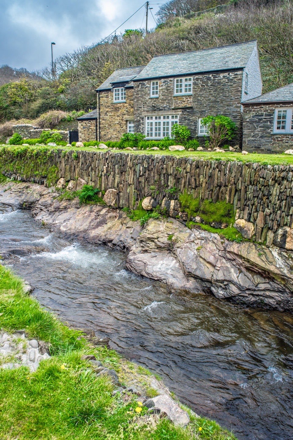 A slate roofed stone cottage above a stream at Boscastle in Cornwall