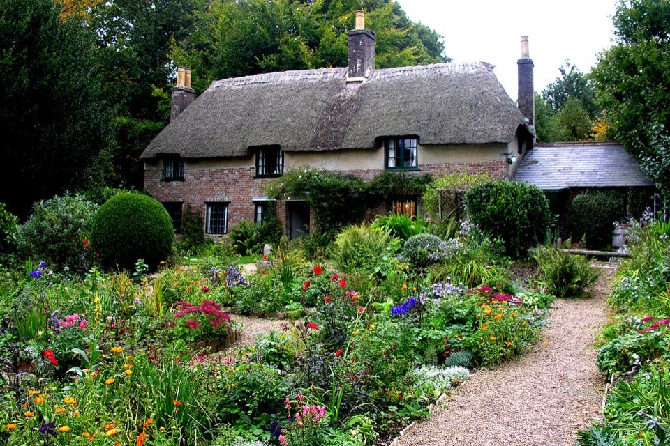 A thatched cottage behind a deep flower garden in Dorset